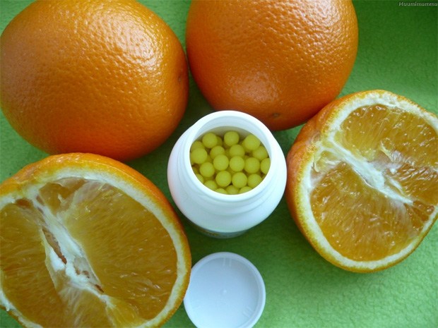 Аскорбиновая кислота в баночке в окружении апельсинов