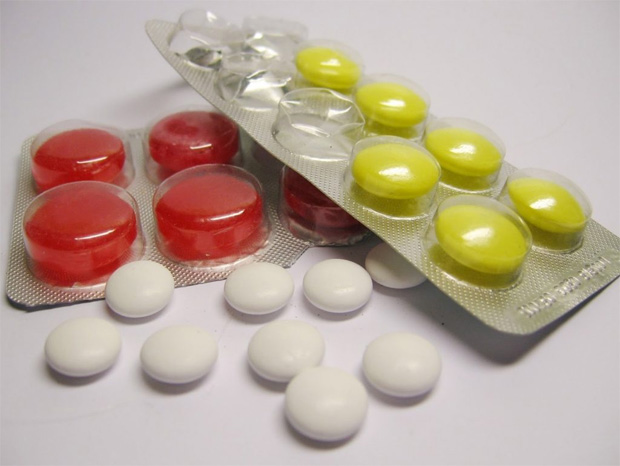 На столе лежит три вида препаратов в таблетках красного, желтого и белого цветов