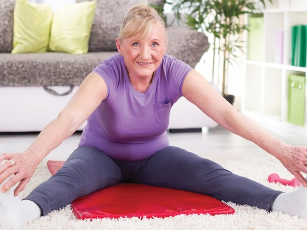 Пожилая женщина выполняет физические упражнения дома