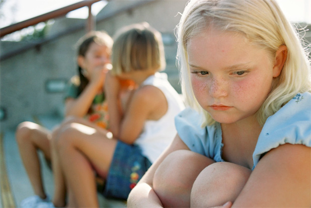 Девочка с веснушками грустит на фоне других детей
