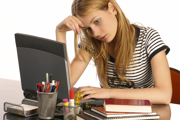 Девушка сидит за ноутбуком, опираясь головой на руку