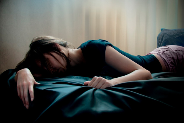Девушка лежит на кровати, уткнувшись лицом в подушку