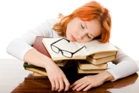 Девушка спит на стопке книг на рабочем месте