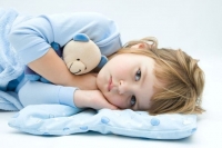 Девочка в голубой пижаме лежит в обнимку с игрушкой